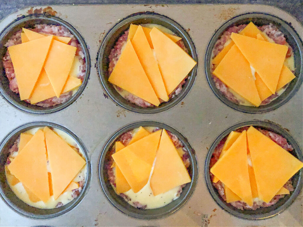 baking tin with keto breakfast muffins ready to bake with cheese on top