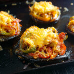 Baking sheet with low carb chicken stuffed portobello mushrooms with Mexican flavors and topped with melted cheese.