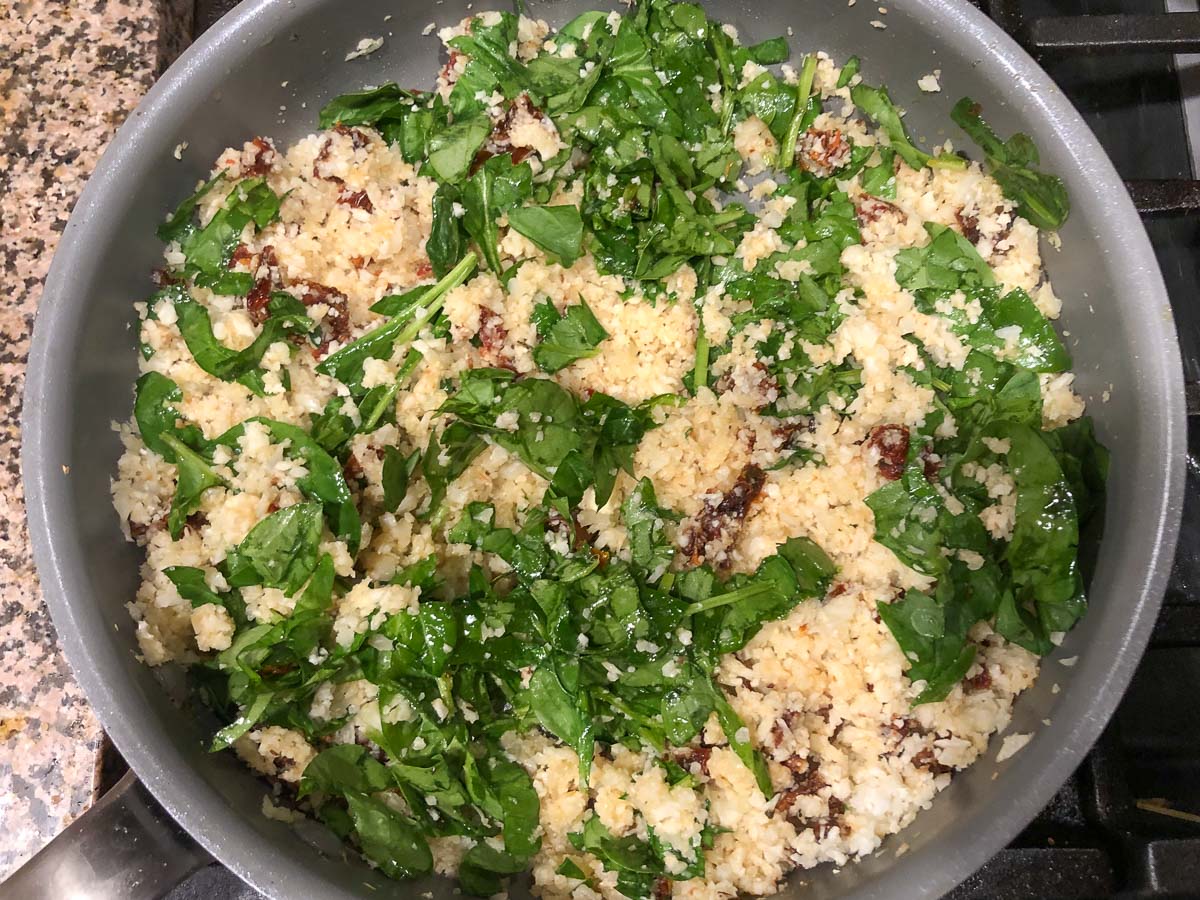 a pan with the rice cooking with spinach