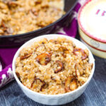 White bowl with keto mushroom cauliflower risotto and a box of brie in the background and fresh mushrooms on the side.