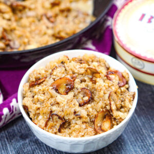 White bowl with keto mushroom cauliflower risotto and a box of brie in the background and fresh mushrooms on the side.