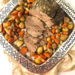 metal platter with slow cooker lamb should and scatter roasted potatoes and carrots with text overlay