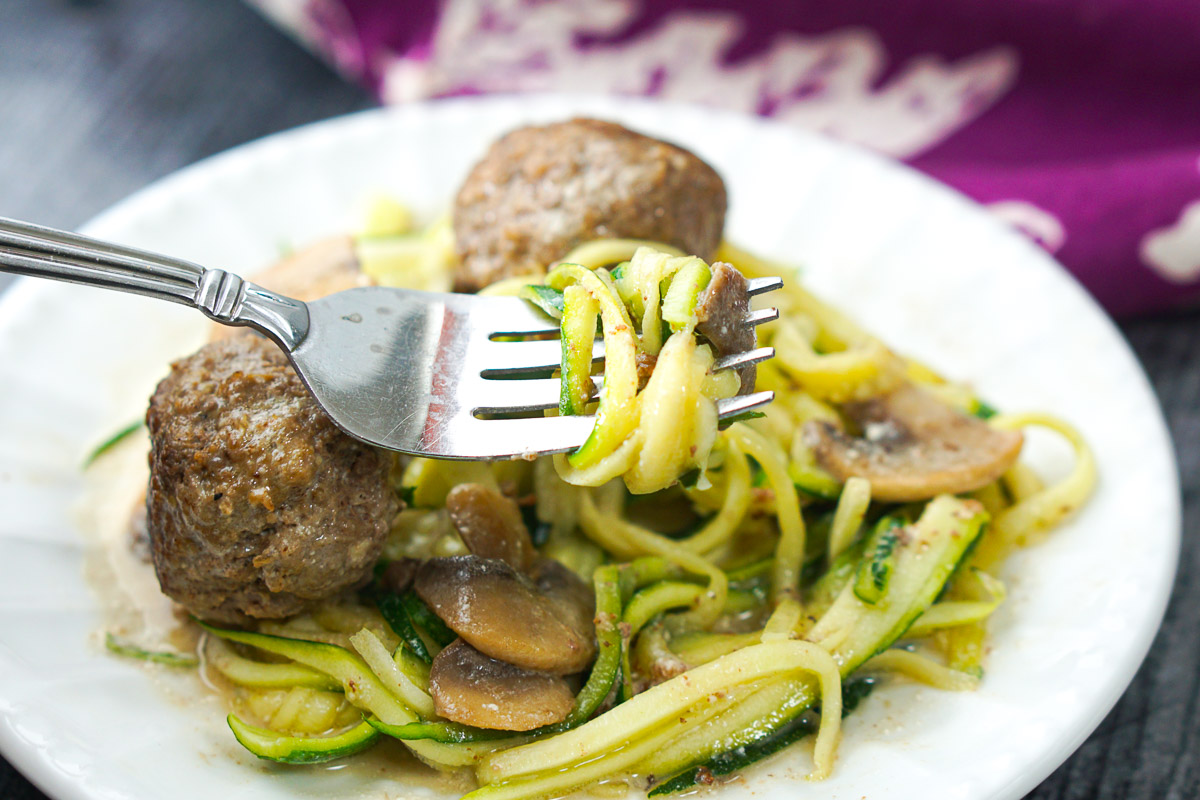 a forkful of zucchini noodles and keto meatballs in the background