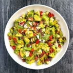 White bowl with keto chunky guacamole with Greek flavors.