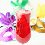 Glass with low carb hurricane drink and Mardi Gras masks in the background.
