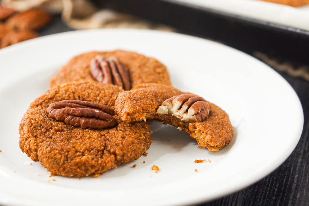 closeup of a 3 healthy pumpkin cookies with pecans on top and bite taken out of one