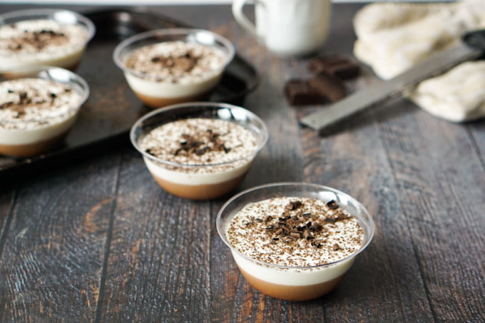 tiramisu gelatin dessert cups with microplane in the background and cookie sheet with more cups