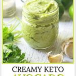jar of creamy keto avocado lime dressing with garlic cloves, cilantro and text