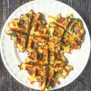 A white plate with 3 small low carb spinach waffles.