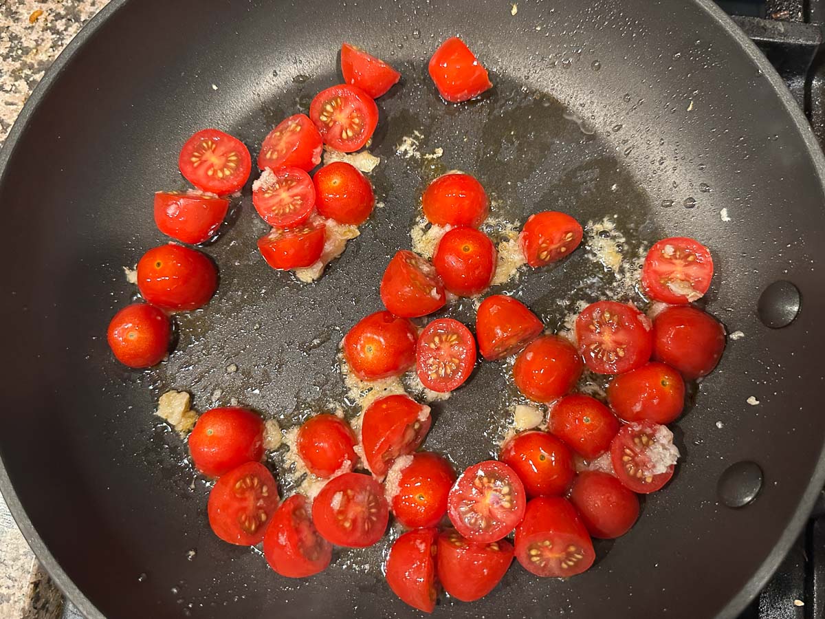 Skillet with sautéed tomatoes and garlic.
