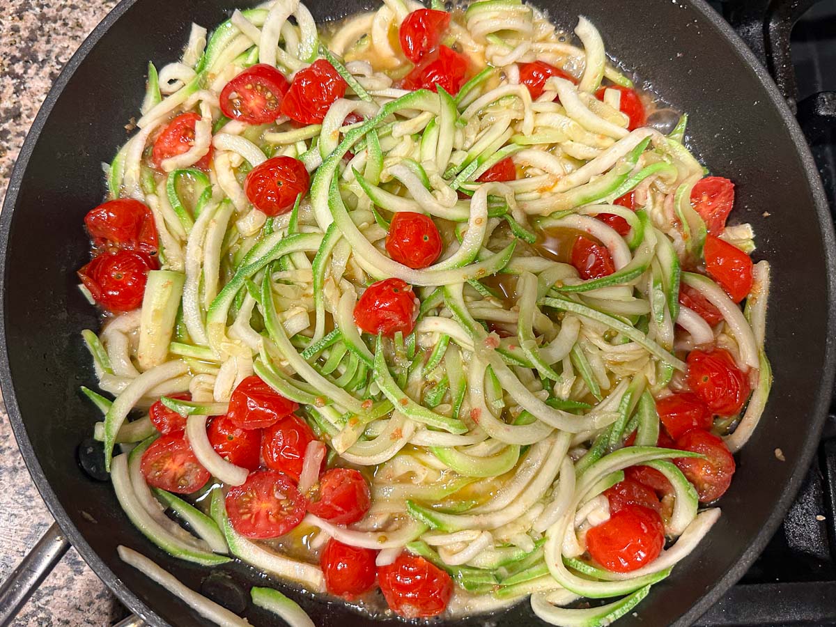 Skillet with the zucchini noodles added to tomatoes.