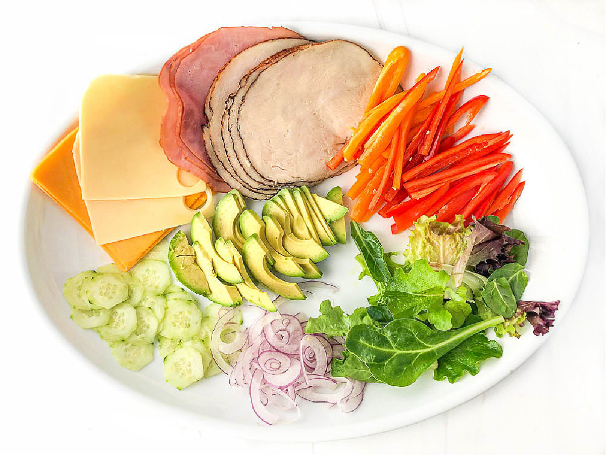 a white platter with fresh sandwich fixings 