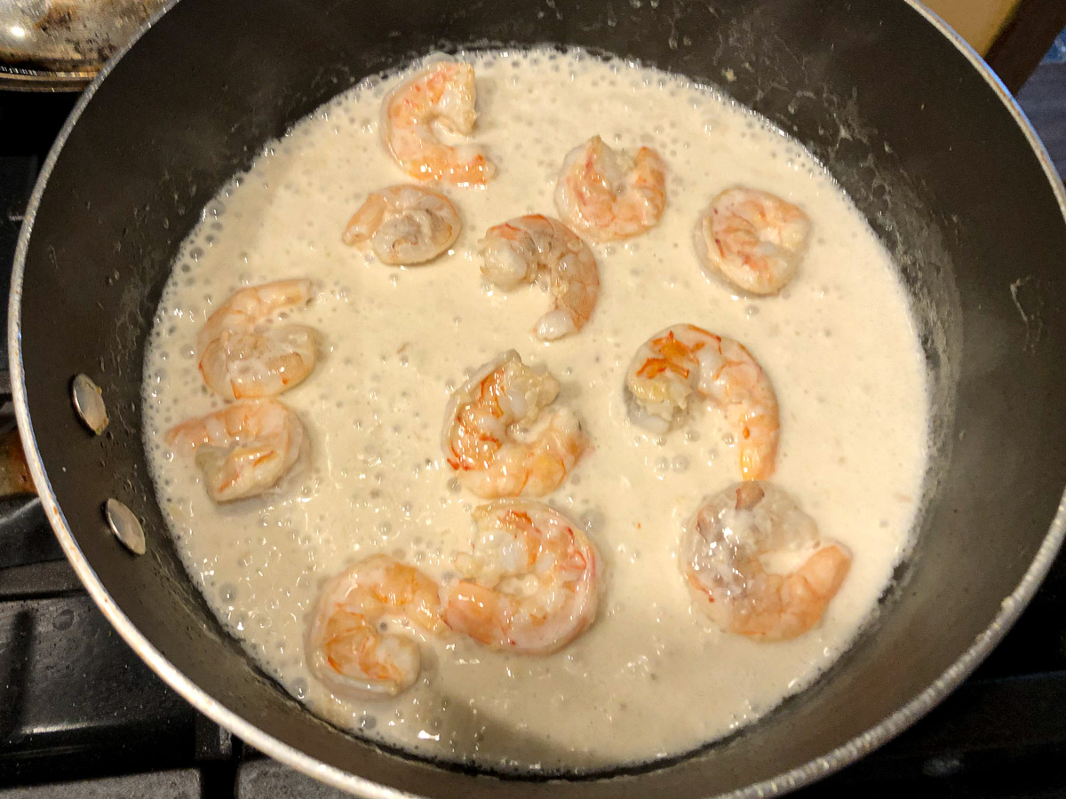 skillet with spices, coconut milk and shrimp