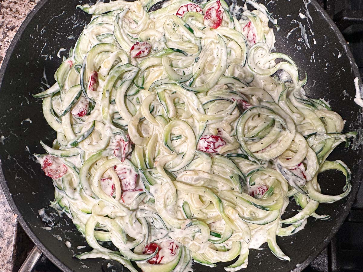 Pan with the zucchini noodles cooking in the creamy keto tomato sauce.