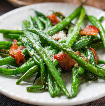closeup of a white plate with green beans and bacon