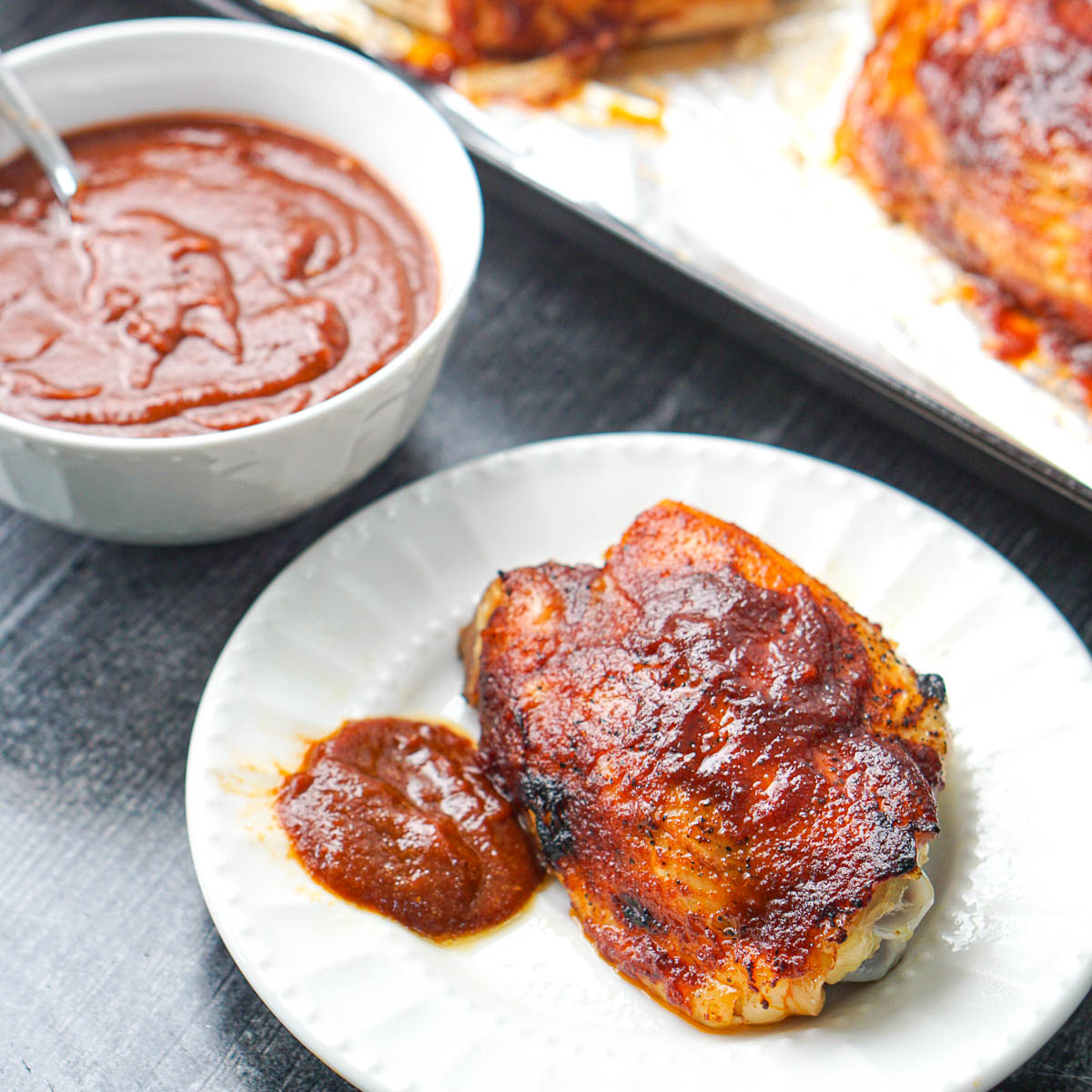 white plate with keto bbq chicken with sauce in background