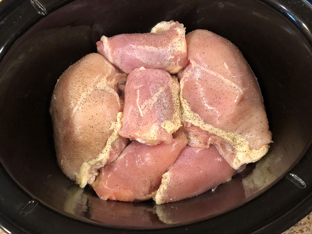 slow cooker with raw pieces of chicken