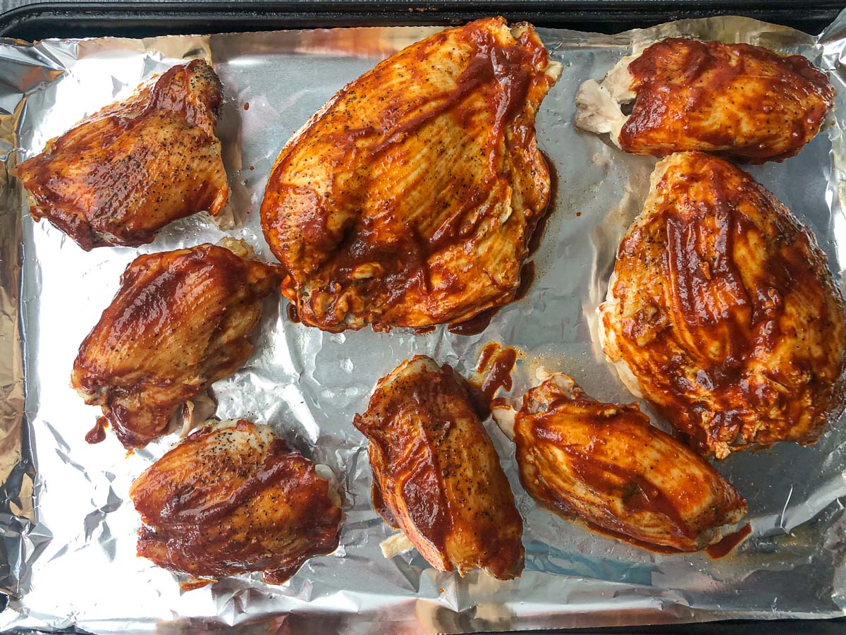 baking sheet with chicken basted in bbq sauce ready to broil