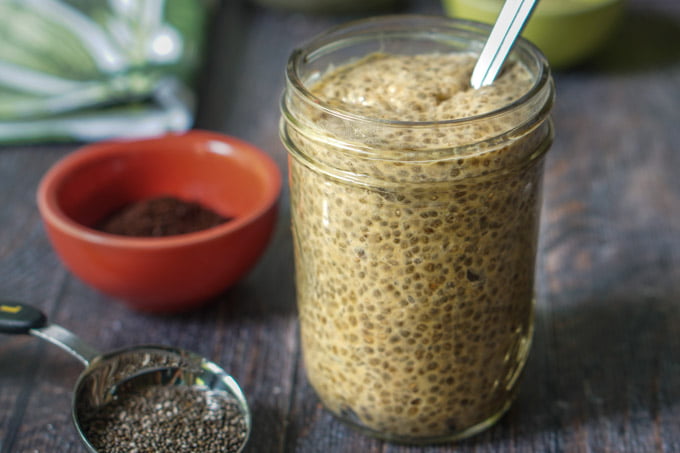 coffee or tea breakfast chia pudding in glass jar with coffee grounds in little red dish and chia seeds