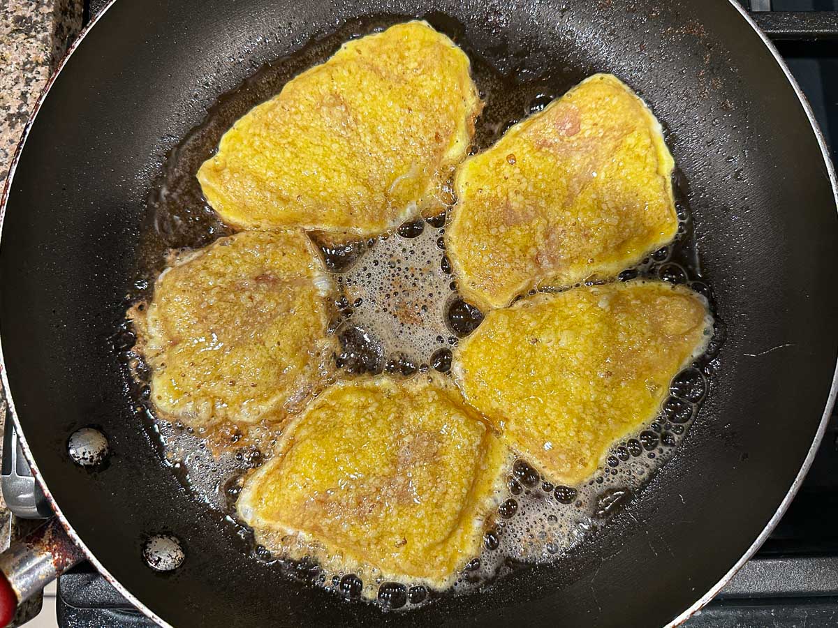 Pan with the battered cutlets browning in butter and oil.
