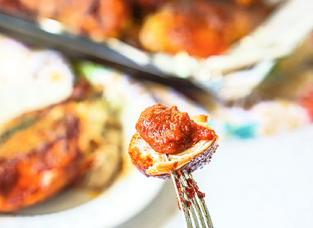 a piece of bbq chicken on a fork with sauce