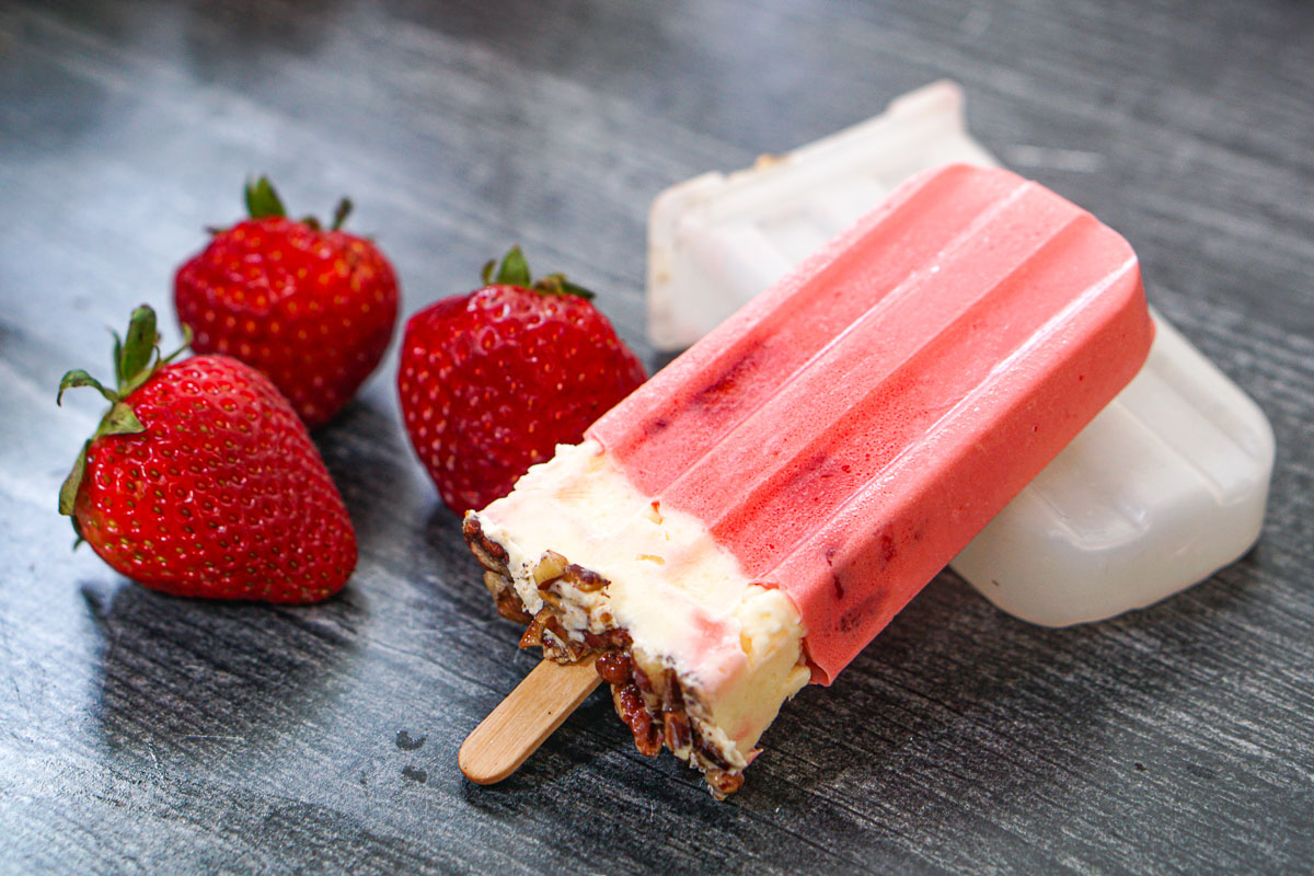 The finished popsicle laying on the mold with a few fresh berries next to it.