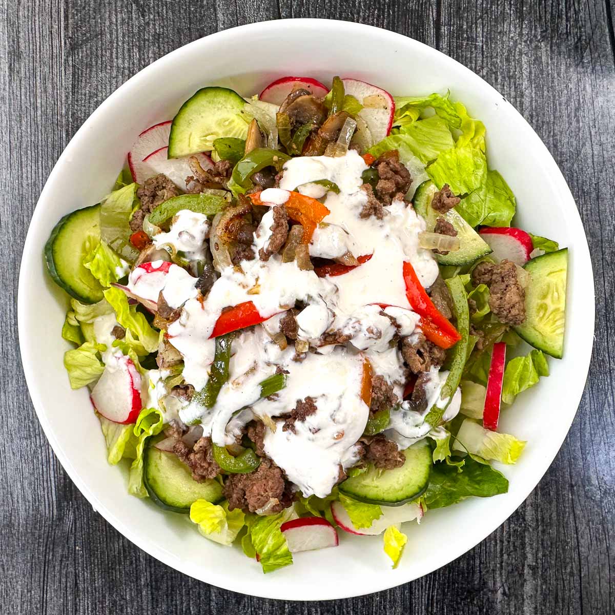 white bowl with keto cheesesteak salad with creamy parmesan dressing