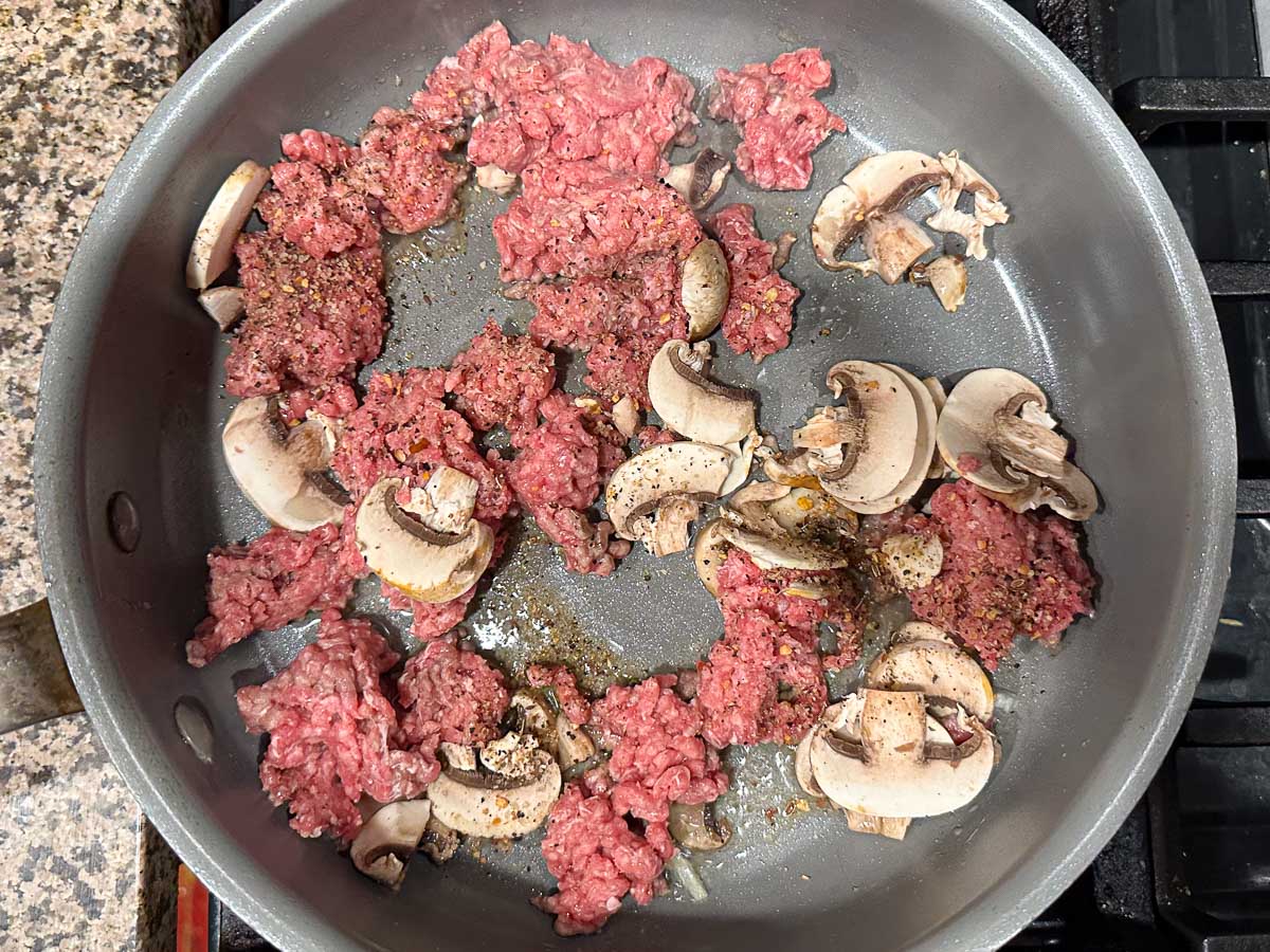 skillet with mushrooms and ground beef browning
