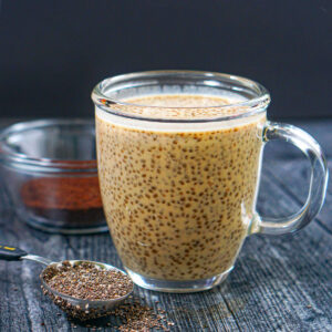Closeup of a glass coffee cup with coffee chia pudding with protein and a spoonful of chia seeds.