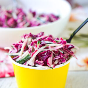yellow cup with keto cucumber slaw with a creamy dressing and spoon
