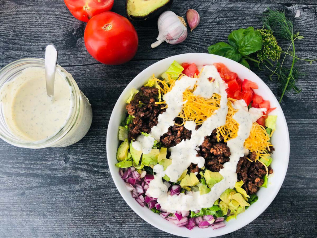 aerial view of keto taco salad with keto ranch dressing and fresh tomatoes, garlic and herbs