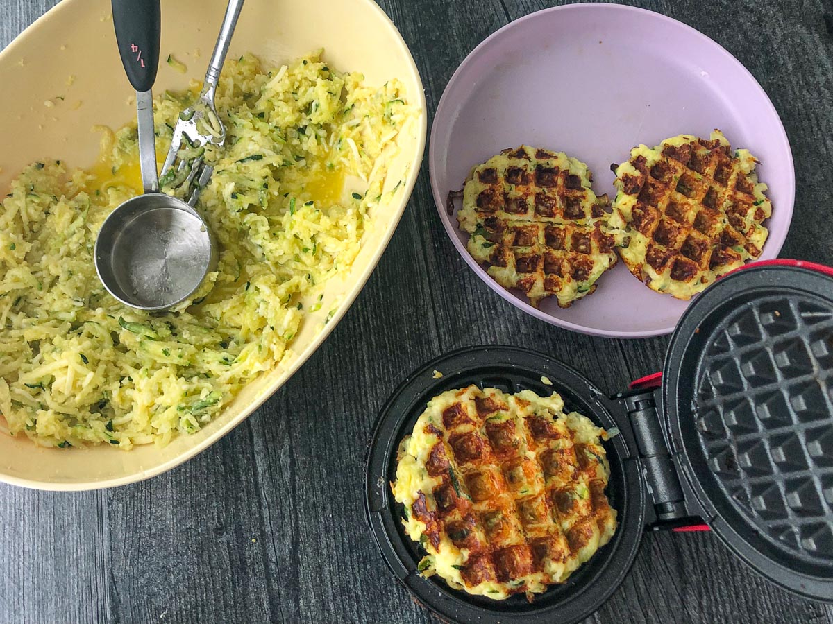 waffle iron and batter with a plate of finished waffles