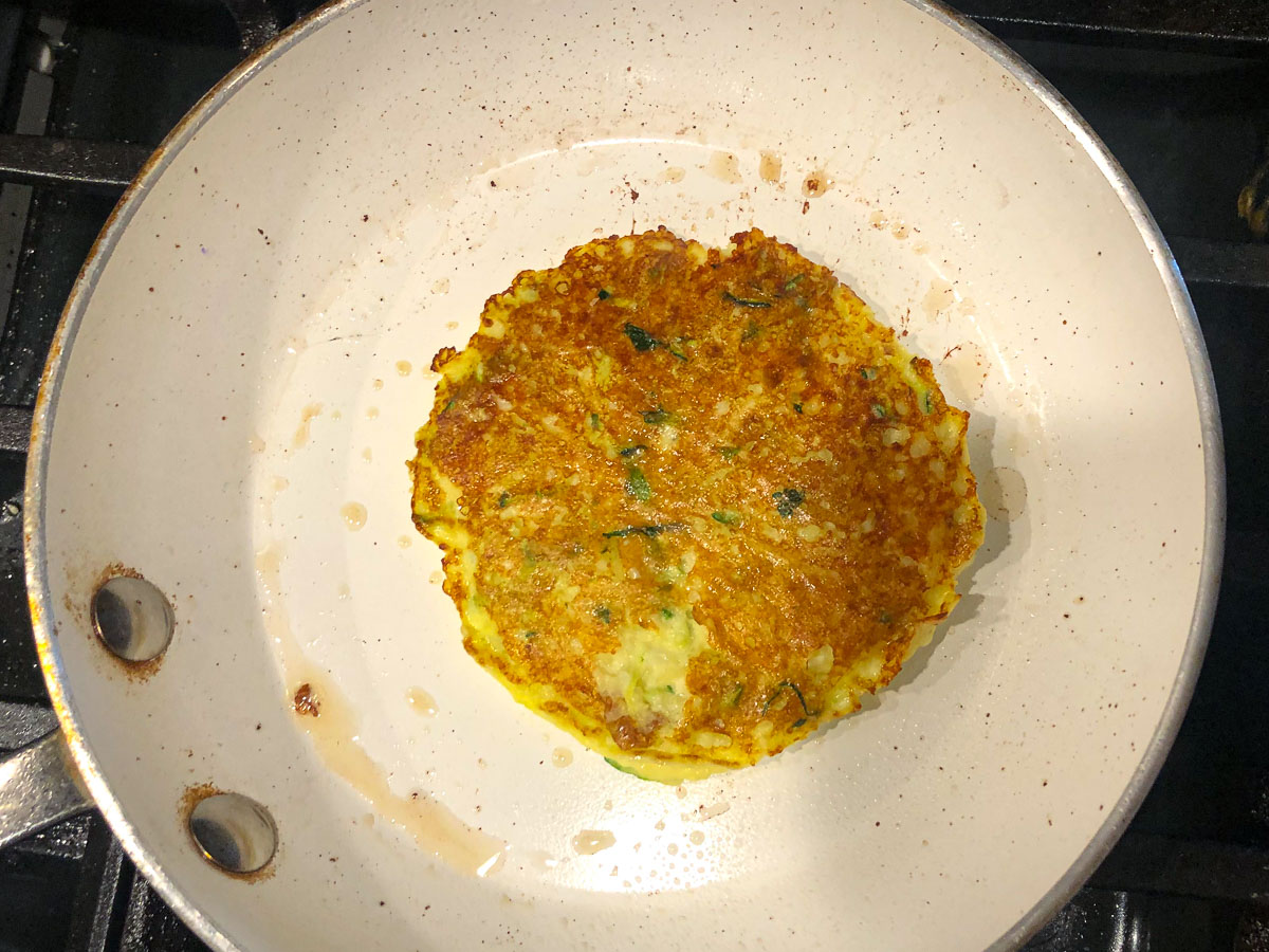 white pan with a zucchini pancake