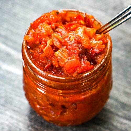 Glass jar with low carb tomato jam with bacon and caramelized onions.