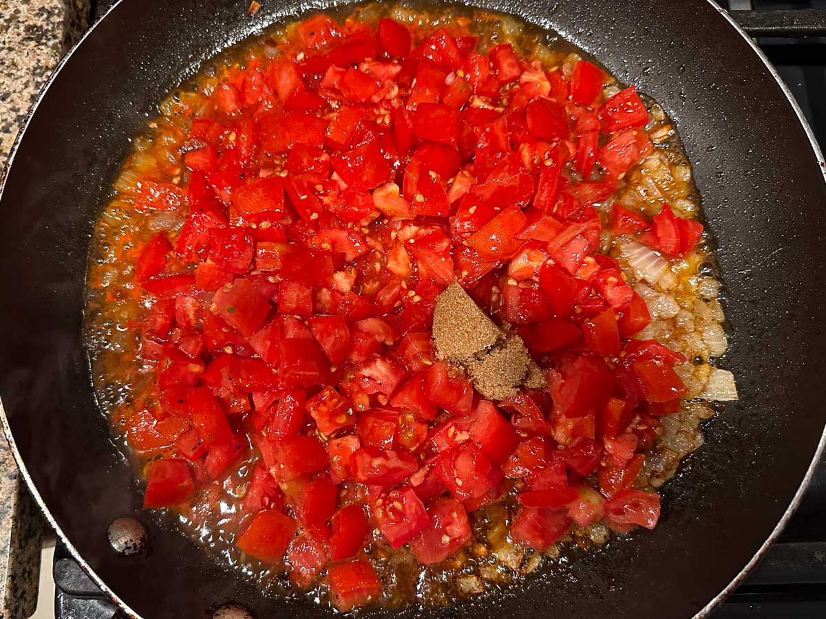Skillet with the tomatoes and sweetener added to the onions.