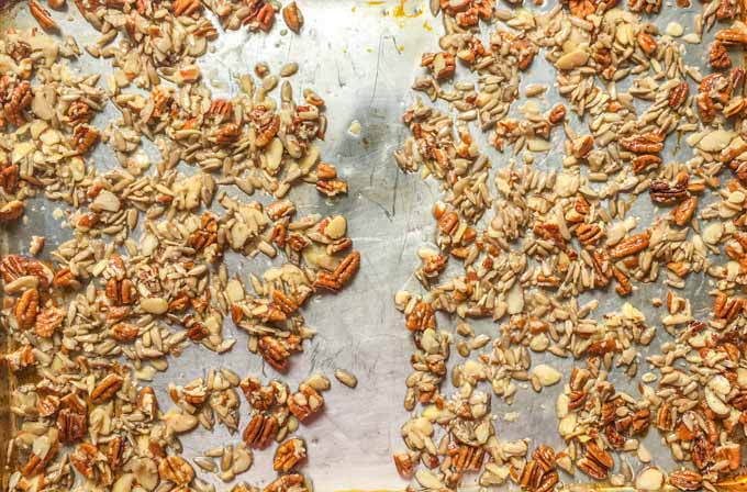 cookie sheet with raw granola ingredients split in two batches