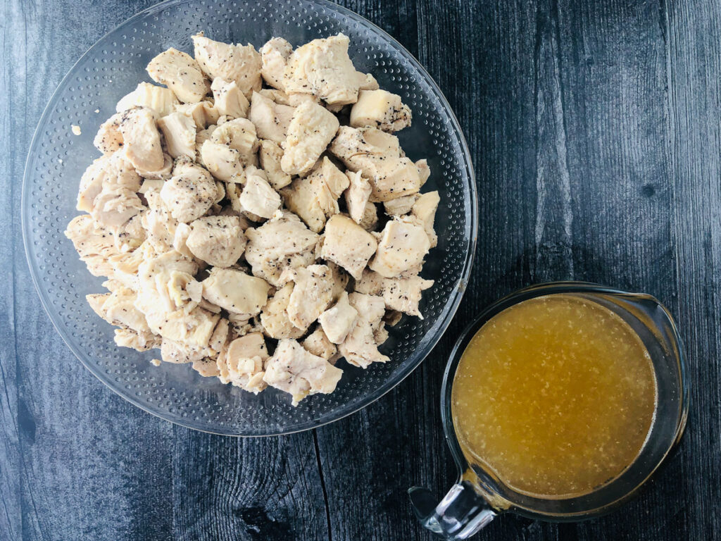 bowl of chopped instant Pot chicken and a cup of chicken broth