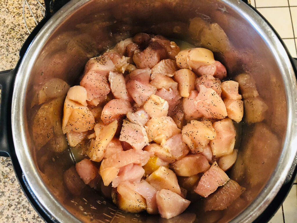 instant pot filled with raw chicken cubes