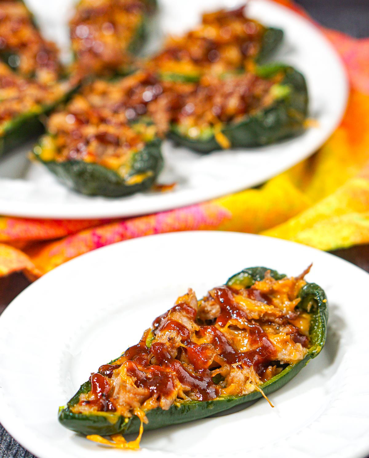 White plates with the finished bbq pork stuffed poblano peppers.