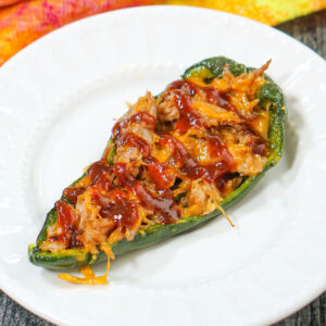 White plate with bbq pulled pork stuffed poblanos.
