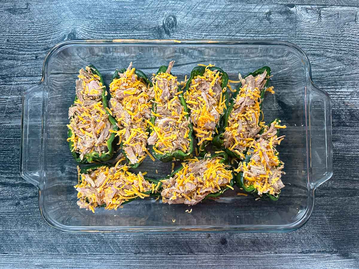 Glass baking dish with the stuffed peppers with meat and cheese ready to bake. 