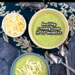 Aerial view of a 2 bowls of keto broccoli cauliflower soup with a bowl of shredded cheddar cheese and spoons and text.