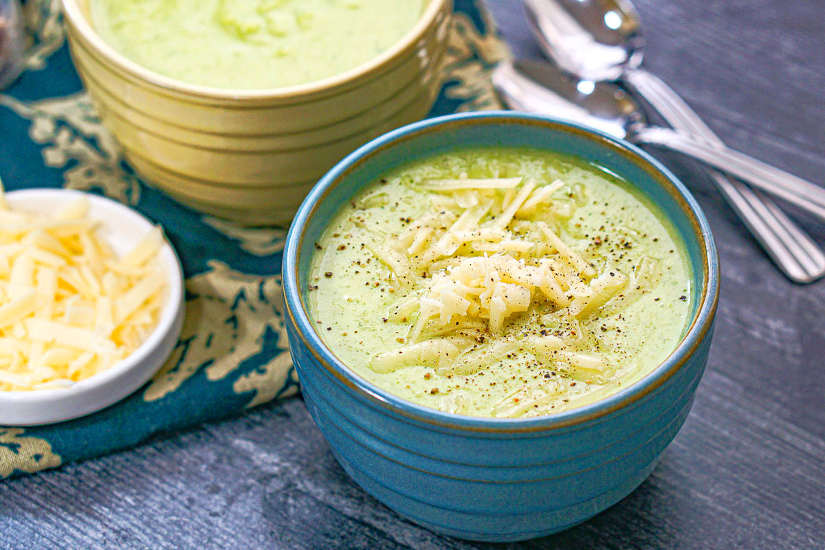 A blue bowl of the finished recipe with a small dish with shredded cheddar cheese.
