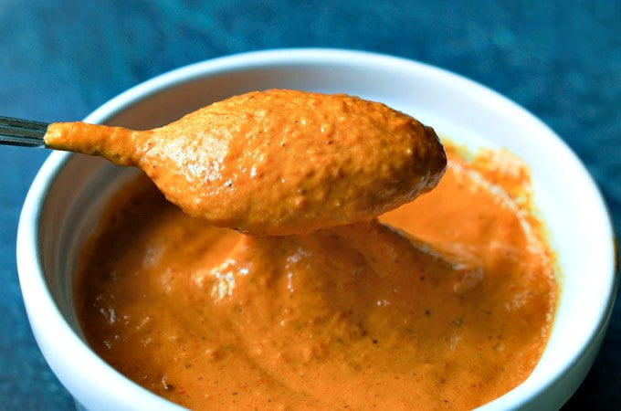 white bowl of roasted red pepper sauce and a spoon