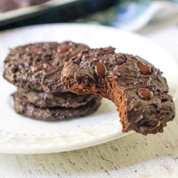 white plate with chocolate keto brownie cookies with a bit taking out