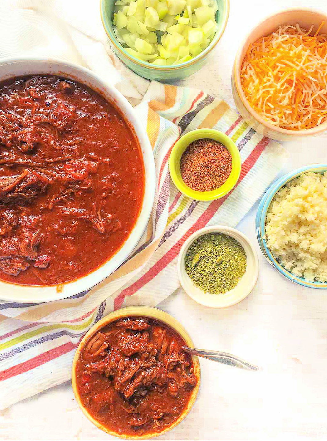 aerial view of bowls of shredded beef chili and condiments