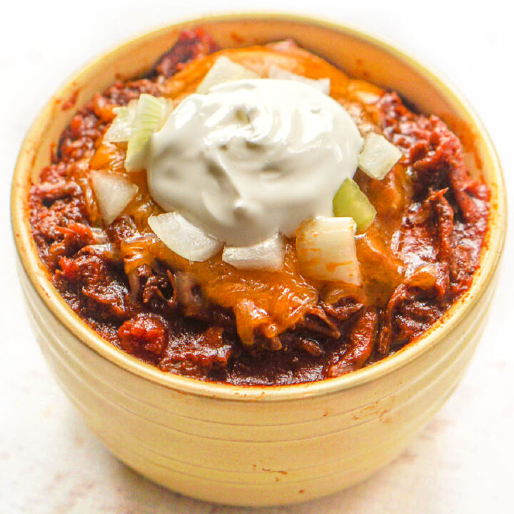 shredded beef chili in a yellow dish topped with sour cream