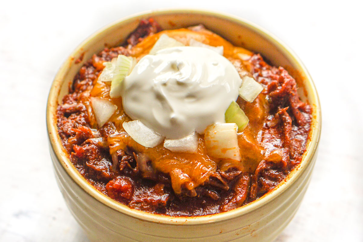 instant pot chili in a yellow dish topped with sour cream