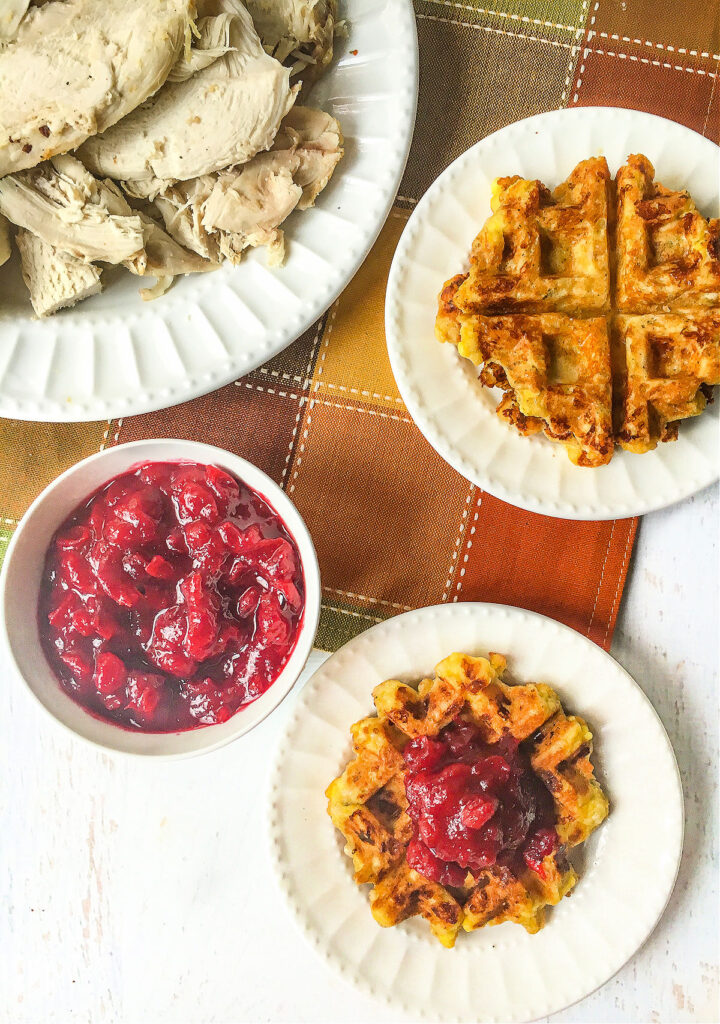 aerial view of white plate with keto stuffing waffles and bowl of cranberry sauce and turkey slices