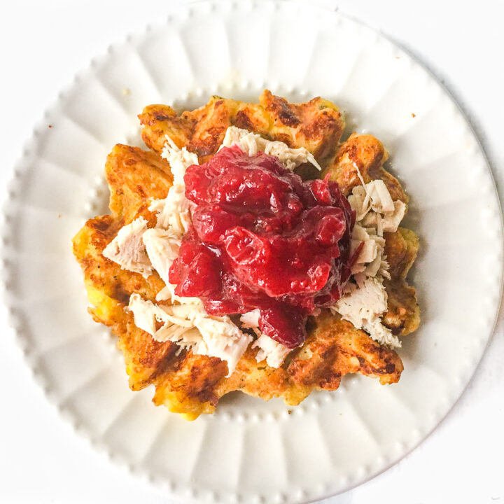 white plate with turkey stuffing waffles topped with cranberry sauce